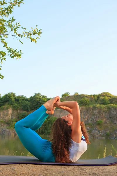 Молодая женщина практикует йогу возле реки — стоковое фото