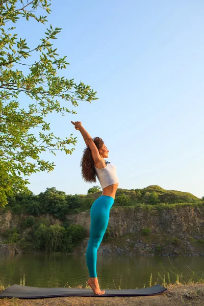 Jeune femme pratique le yoga près de la rivière — Photo