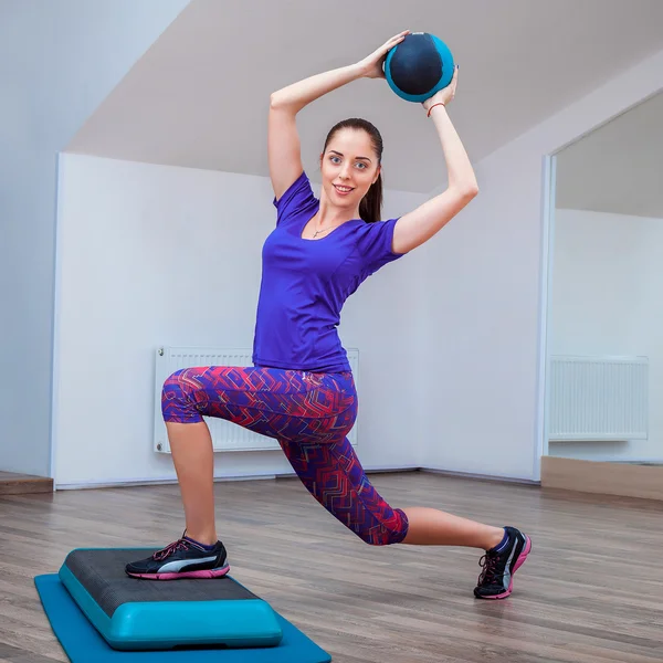 Fitness-Mädchen in Turnschuhen posiert auf Trittbrett mit Ball — Stockfoto