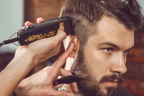 Las manos del joven peluquero haciendo corte de pelo a un hombre atractivo en la barbería —  Fotos de Stock