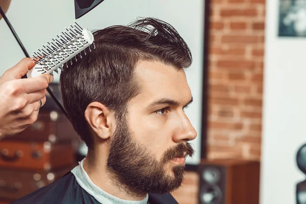 Las manos de joven peluquero haciendo corte de pelo atractivo hombre en la barbería — Foto de Stock