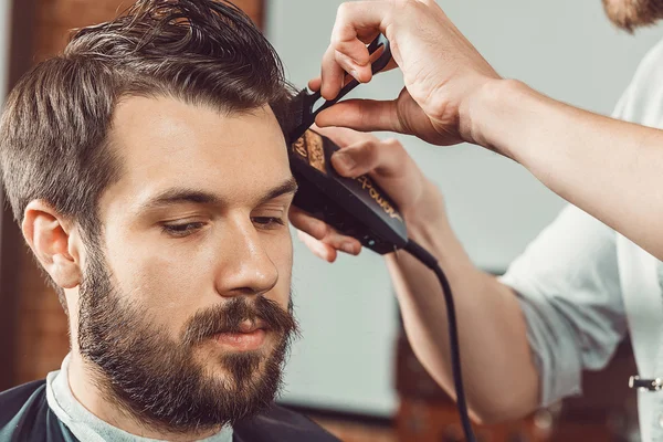 Las manos de joven peluquero haciendo corte de pelo atractivo hombre en la barbería — Foto de Stock