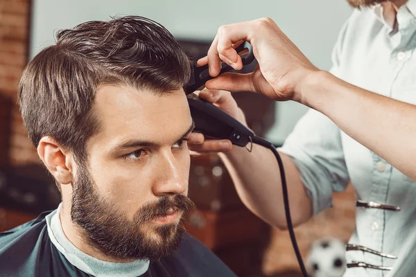 Las manos de joven peluquero haciendo corte de pelo atractivo hombre en la barbería — Foto de Stock