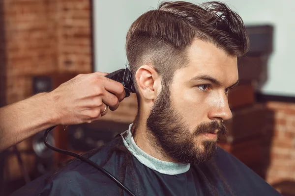 Las manos del joven peluquero haciendo corte de pelo a un hombre atractivo en la barbería — Foto de Stock