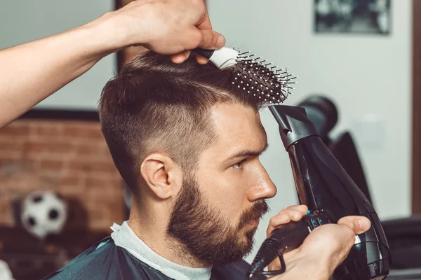 Las manos del joven peluquero haciendo corte de pelo a un hombre atractivo en la barbería — Foto de Stock