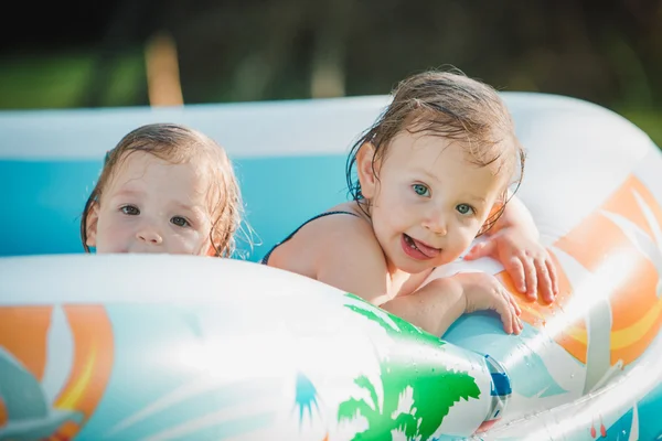 As duas meninas pequenas que jogam com brinquedos na piscina inflável no dia ensolarado do verão — Fotografia de Stock