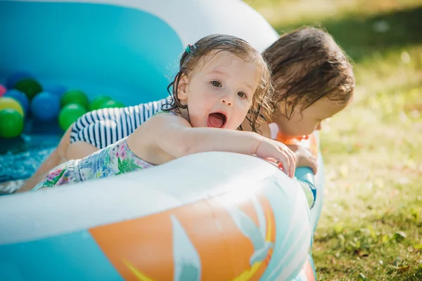 Les deux petites filles de bébé jouant avec des jouets dans la piscine gonflable dans la journée ensoleillée d'été — Photo