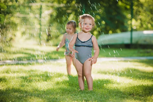 Les deux petites filles jouant avec arroseur de jardin . — Photo