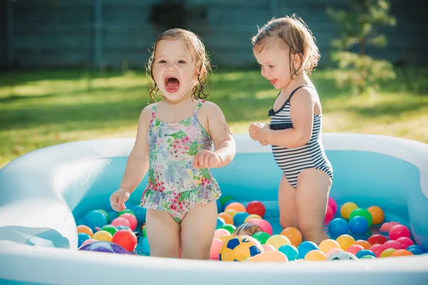 Dwa małe Niemowlęta Dziewczynki bawi się zabawkami w nadmuchiwany basen w słoneczny dzień lata — Zdjęcie stockowe
