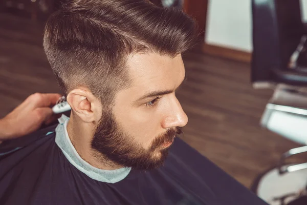 Händerna på unga frisör gör frisyr till attraktiv man i barbershop — Stockfoto