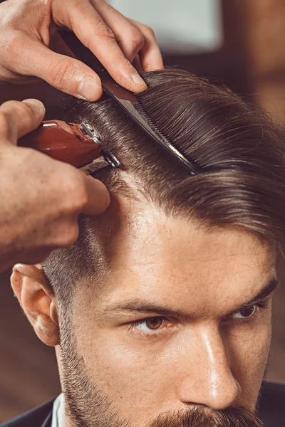 Las manos del joven peluquero haciendo corte de pelo a un hombre atractivo en la barbería —  Fotos de Stock