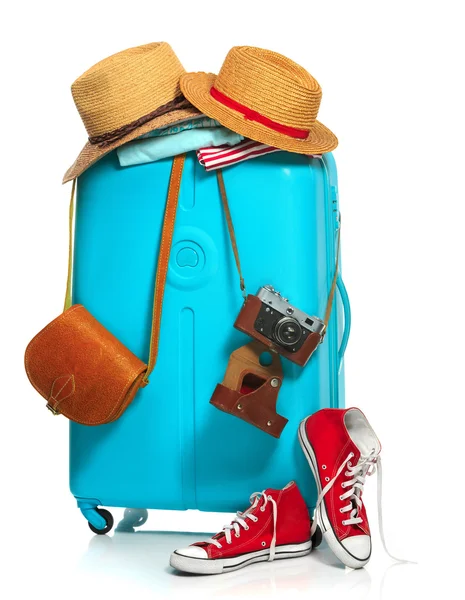 A mala azul, tênis, roupas, chapéu e câmera retro no fundo branco . — Fotografia de Stock