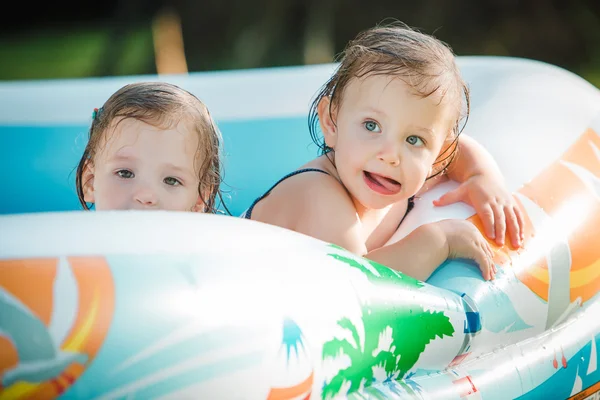 Dwa małe Niemowlęta Dziewczynki bawi się zabawkami w nadmuchiwany basen w słoneczny dzień lata — Zdjęcie stockowe