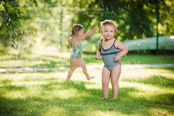 Les deux petites filles jouant avec arroseur de jardin . — Photo