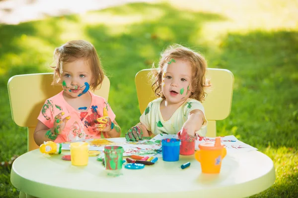 Dvou - letý holky malování obrazů plakát společně proti zelený trávník — Stock fotografie