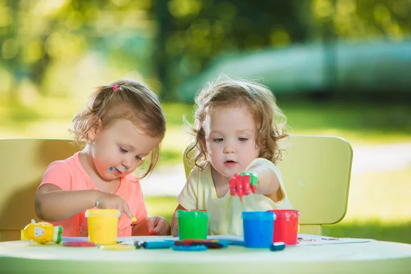 Dos años de edad, las niñas pintando con pinturas de póster juntos contra el césped verde — Foto de Stock