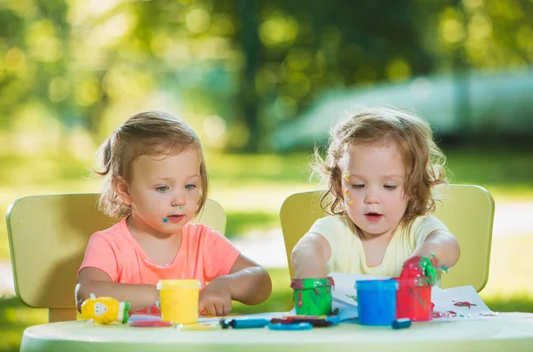 Dos años de edad, las niñas pintando con pinturas de póster juntos contra el césped verde —  Fotos de Stock