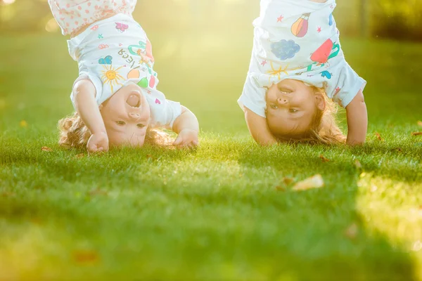 Дві маленькі дівчатка висять догори ногами — стокове фото