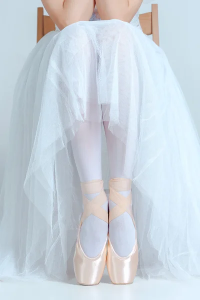 Ballerine professionnelle assise avec ses chaussures de ballet sur le fond gris — Photo