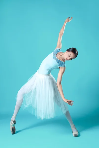 Ballerina in witte jurk poseren op tenen, studio achtergrond. — Stockfoto