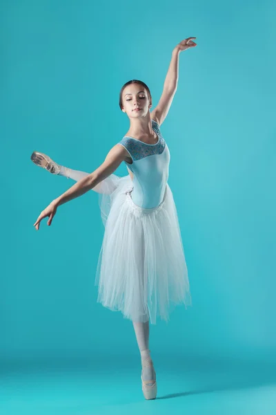 Ballerina in witte jurk poseren op tenen, studio achtergrond. — Stockfoto