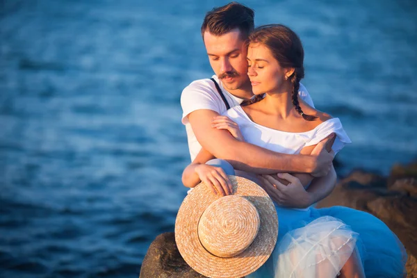 Mutlu genç romantik çift plajda dinleniyor ve gün batımını seyrediyor. — Stok fotoğraf