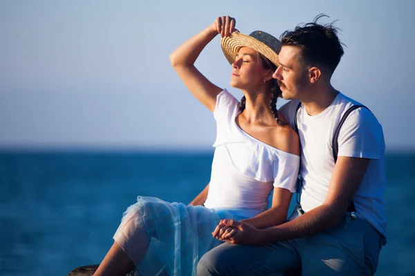 Glad ung romantisk par avkopplande på stranden tittar på solnedgången — Stockfoto
