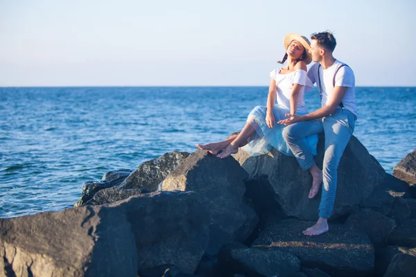 Glad ung romantisk par avkopplande på stranden tittar på solnedgången — Stockfoto