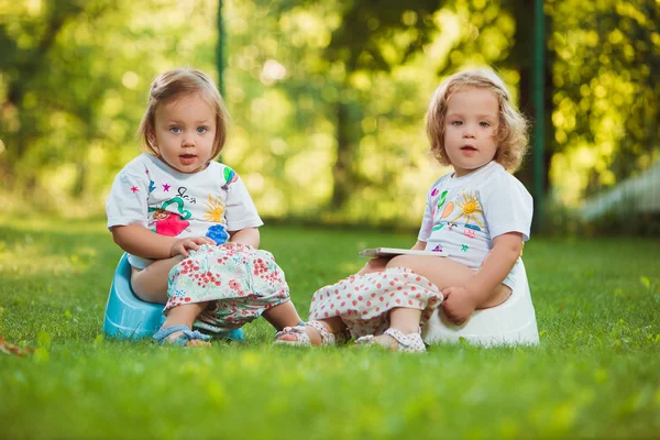 The two little baby girls sitting on pots — Stock Photo, Image