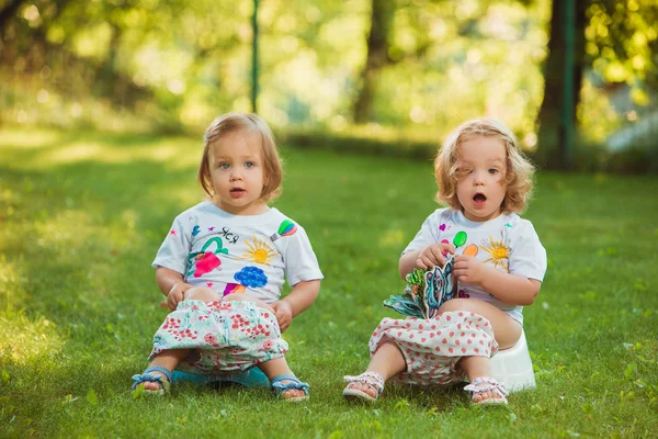 Två lite baby flickor sitter på krukor — Stockfoto