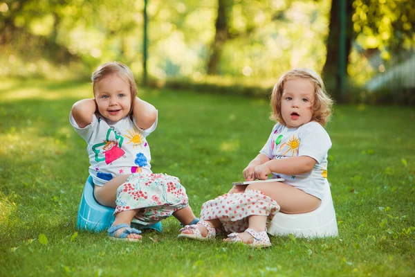 The two little baby girls sitting on pots — Stock Photo, Image