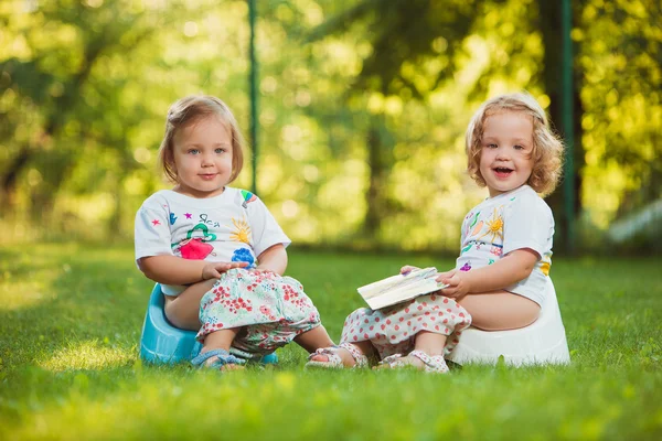 Två lite baby flickor sitter på krukor — Stockfoto