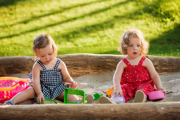 As duas garotinhas brincando de brinquedos na areia — Fotografia de Stock