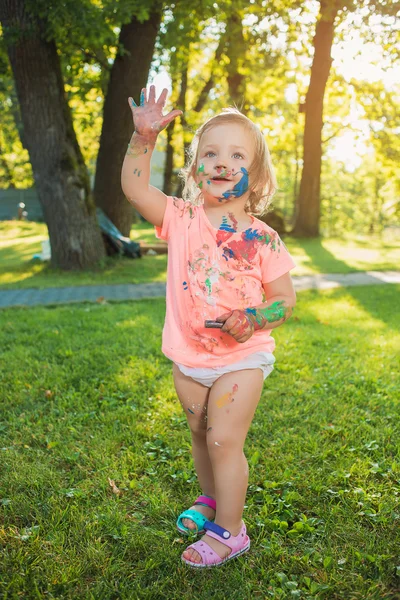İki yaşındaki kız yeşil çim karşı renklerde lekeli — Stok fotoğraf