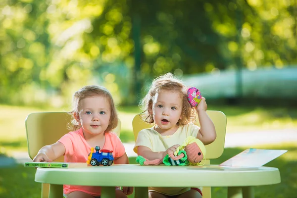 Дві маленькі дівчатка грають в іграшки на піску — стокове фото