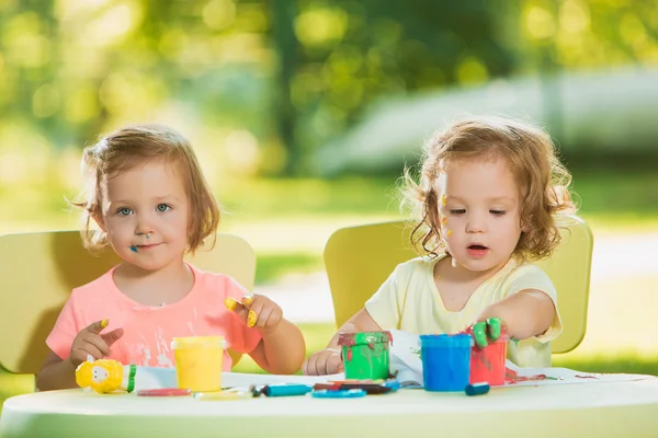 Dvou - letý holky malování obrazů plakát společně proti zelený trávník — Stock fotografie