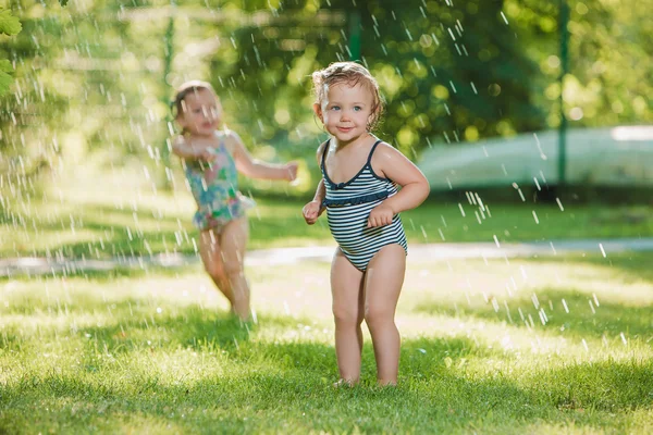 Les deux petites filles jouant avec arroseur de jardin . — Photo