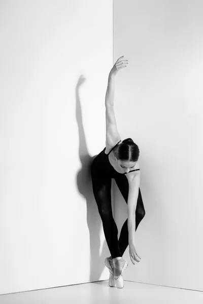 Ballerina in zwarte outfit poseren op pointe schoenen, studio achtergrond. — Stockfoto