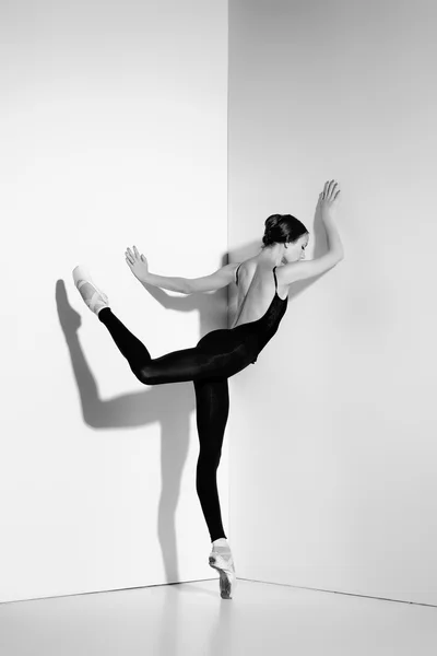 Ballerina in zwarte outfit poseren op pointe schoenen, studio achtergrond. — Stockfoto