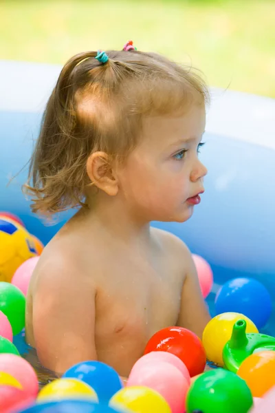 La petite fille jouant avec des jouets dans la piscine gonflable dans la journée ensoleillée d'été — Photo