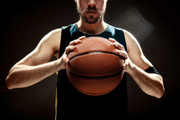 Vista de silueta de un jugador de baloncesto sosteniendo la pelota de baloncesto sobre fondo negro —  Fotos de Stock