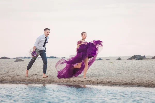 Young romantic couple running on the beach of sea — Stock Photo, Image