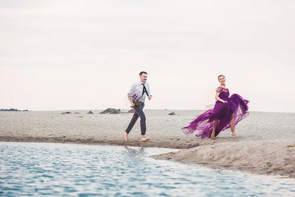 Young romantic couple running on the beach of sea — Stock Photo, Image