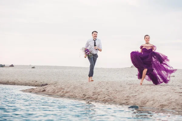 Молодая романтическая пара бегает по морскому пляжу — стоковое фото
