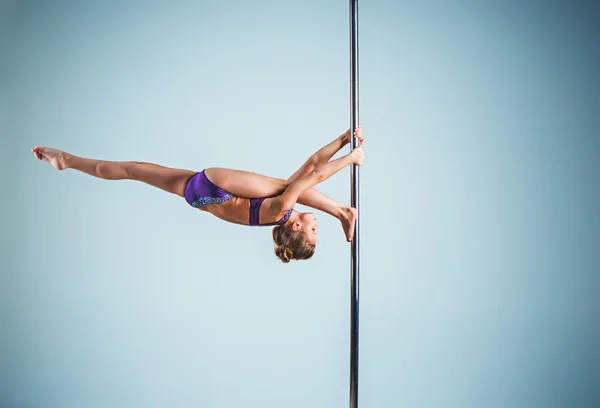 Het sterke en gracieuze jonge meisje uitvoeren van acrobatische oefeningen op een pylon — Stockfoto