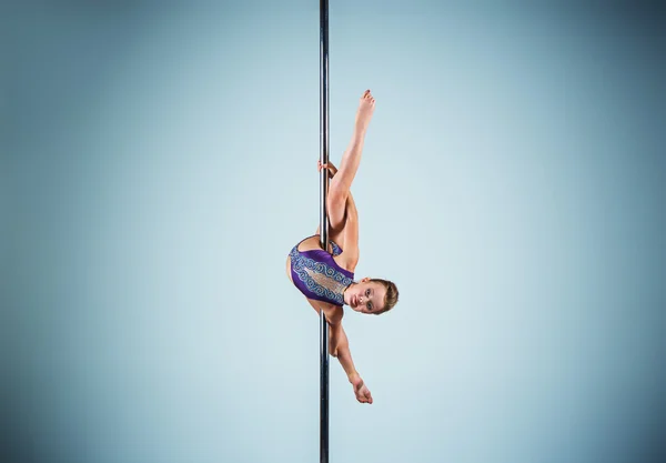 La joven fuerte y elegante que realiza ejercicios acrobáticos en el pilón —  Fotos de Stock