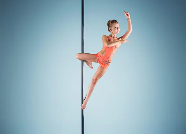 La jeune fille forte et gracieuse effectuant des exercices acrobatiques sur pylône — Photo
