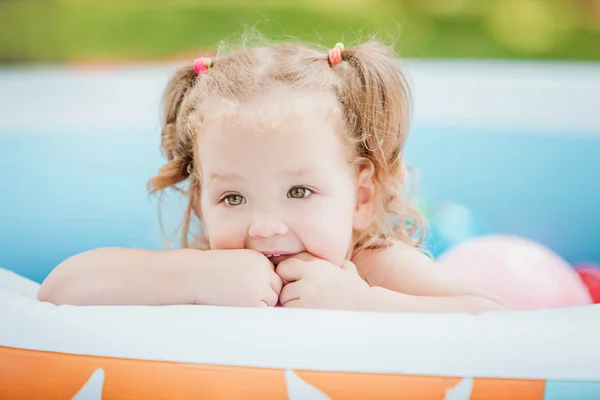 Маленька дівчинка грає з іграшками в надувному басейні в літній сонячний день — стокове фото
