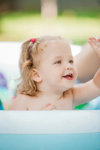 La petite fille jouant avec des jouets dans la piscine gonflable dans la journée ensoleillée d'été — Photo