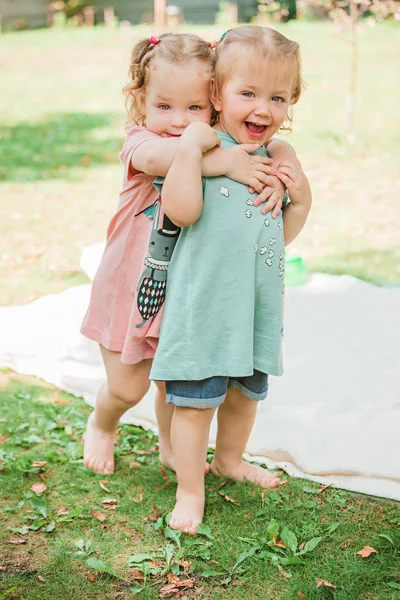 The two little baby girls playing against green grass — Stock Photo, Image